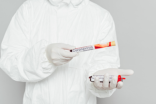 cropped view of epidemiologist in hazmat suit holding test tubes with blood samples isolated on grey