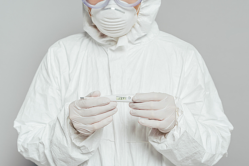 cropped view of epidemiologist holding thermometer showing high temperature isolated on grey