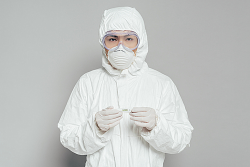 asian epidemiologist  while holding thermometer showing high temperature on grey background