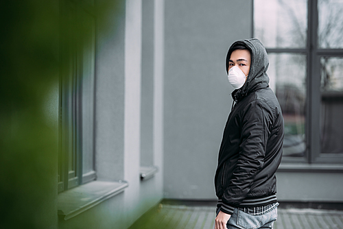 selective focus of young asian man in respirator mask  while standing on street