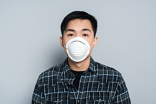 young asian man in respirator mask  on grey background