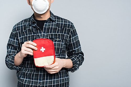 cropped view of man in respirator mask showing first aid kit isolated on grey