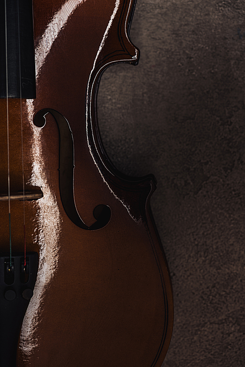 top view of classical cello on grey textured surface in darkness