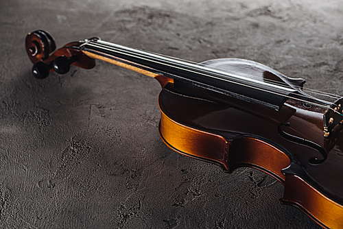 wooden classical violoncello in darkness on textured surface