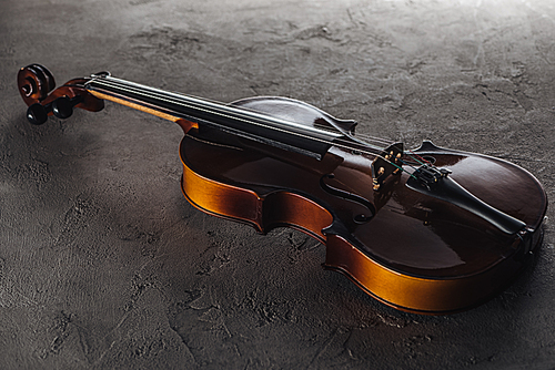 wooden classic violoncello in darkness on textured surface