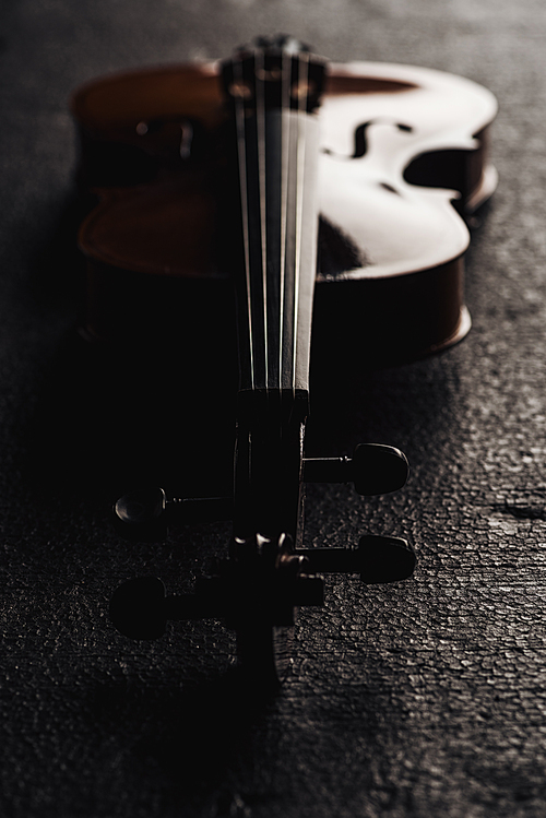close up of strings on cello in darkness on grey textured background