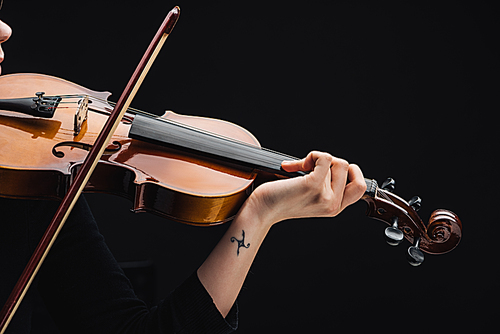 partial view of woman with tattoo playing cello with bow isolated on black