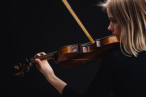 young concentrated woman playing cello with bow isolated on black with copy space