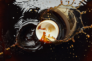 Overturned white porcelain cup with black coffee and splash