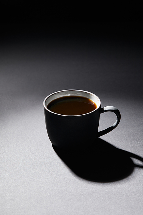 Full cup of coffee on dark textured surface