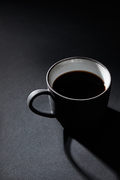 Cup of black coffee on dark textured surface