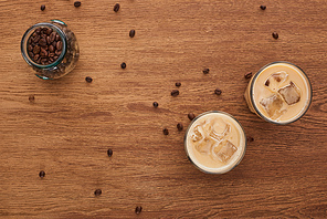 top view of ice coffee and coffee grains on wooden table