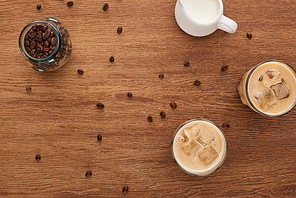 top view of ice coffee, milk and coffee grains on wooden table
