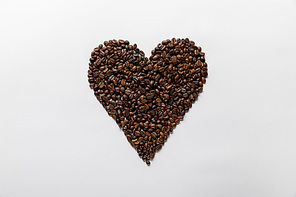 top view of  heart made of fresh coffee grains on white background