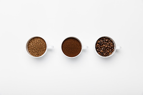 flat lay with three types of coffee grinding in cups on white background
