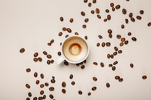 top view of coffee cup with foam on beige background with coffee grains