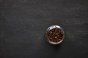 Glass jar with coffee beans on dark wooden surface