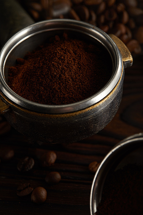 Portafilter with fresh ground coffee under dark surface with coffee beans