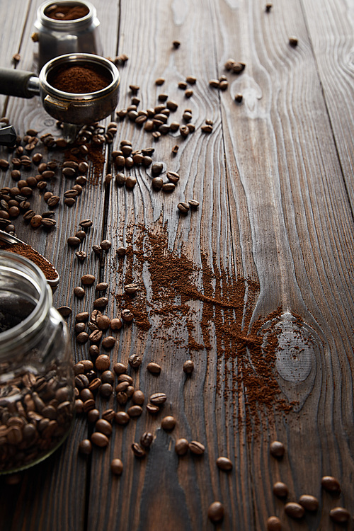 Glass jar near portafilter and part of geyser coffee maker on dark wooden surface with coffee beans