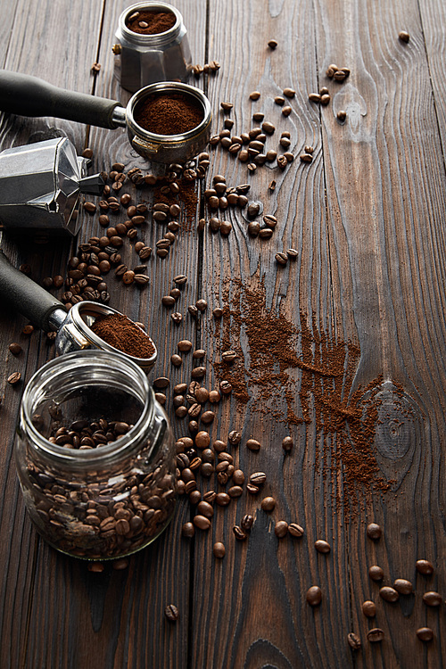 Dark wooden surface with glass jar, portafilters, geyser coffee maker and coffee beans