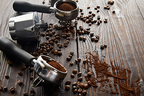 Geyser coffee maker between portafilters on dark brown wooden surface with coffee beans