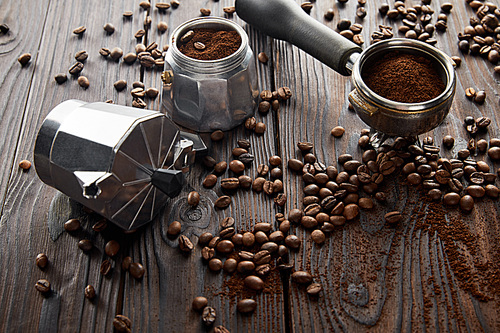 Geyser coffee maker near portafilter on wooden surface with coffee beans