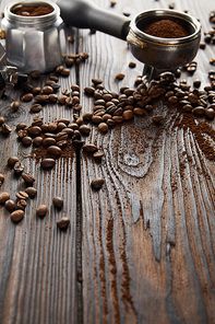 Portafilter near geyser coffee maker on dark wooden surface with coffee beans