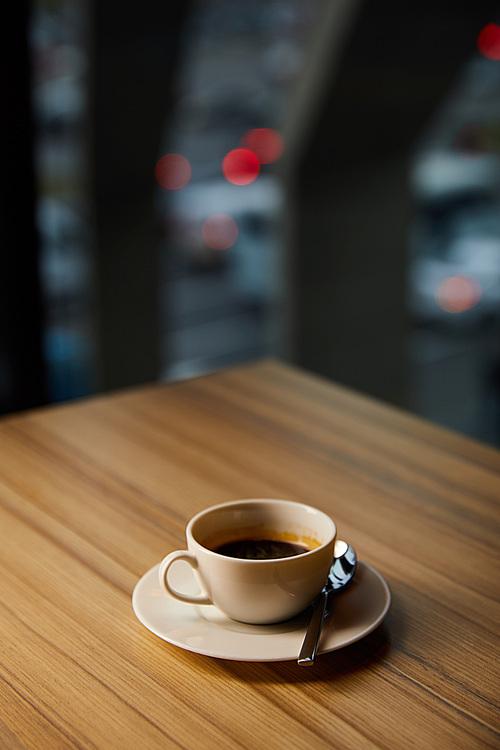 selective focus of cup with coffee on wooden table in cafe