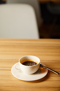 selective focus of cup with coffee near spoon in cafe