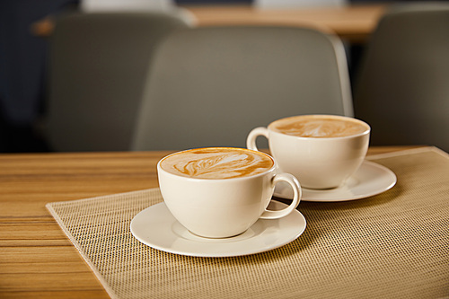 selective focus of creamy cappuccino in white cups on table