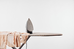 Shirt and iron on ironing board isolated on grey