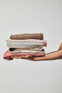 Cropped view of woman holding folded ironed clothes isolated on grey