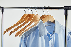 Straight rack, wooden hangers and blue shirt isolated on grey