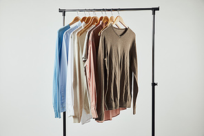 Straight rack, wooden hangers and male clothes isolated on grey