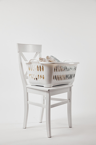 Wooden chair with plastic laundry basket on white