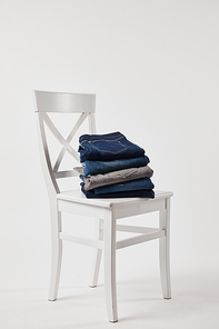 Wooden chair with folded denim pants on white