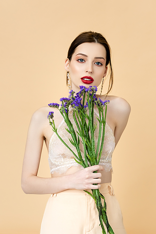 beautiful woman holding purple flowers isolated on beige