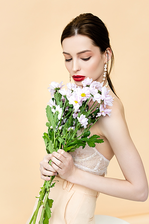 beautiful woman holding blooming flowers isolated on beige