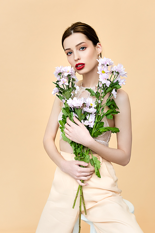 beautiful woman with red lips holding blooming flowers isolated on beige