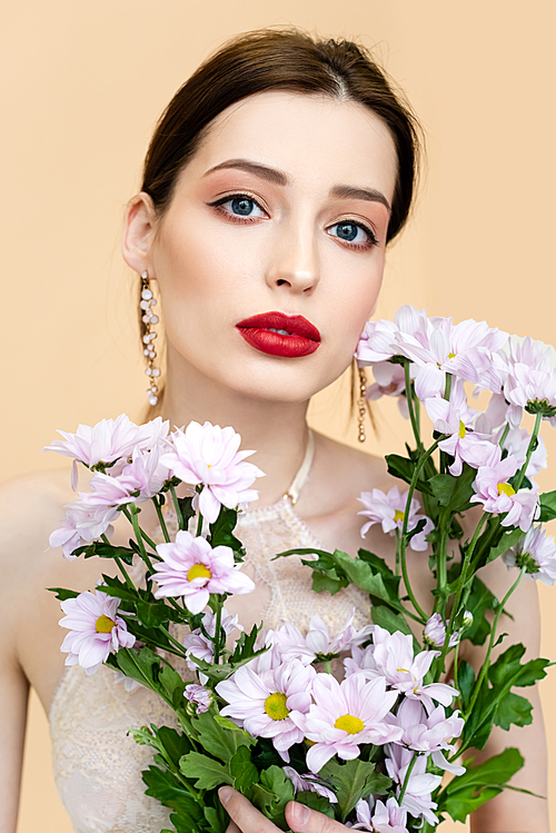 young woman holding blooming chrysantemum flowers isolated on beige