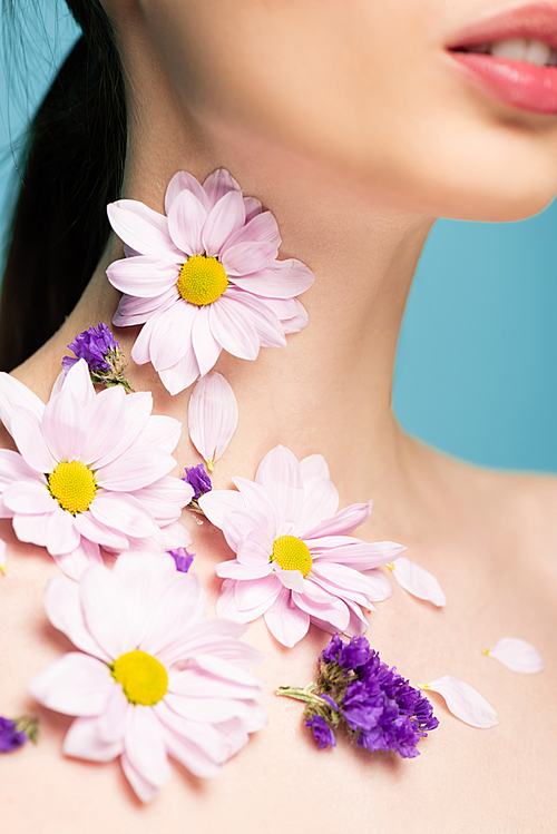 cropped view of young woman with flowers on neck isolated on blue