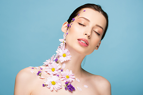 naked young woman with flowers and closed eyes isolated on blue