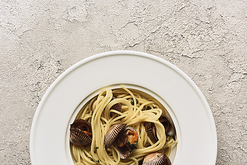 top view of delicious pasta with mollusks on white textured background