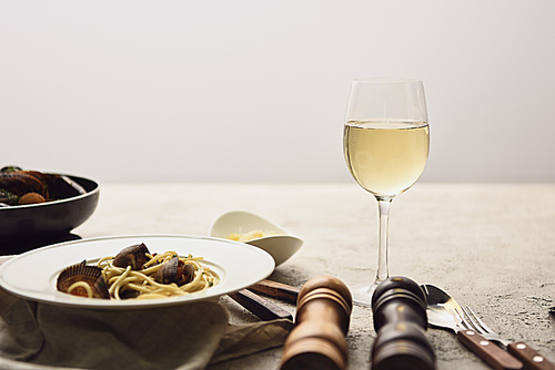 delicious pasta with seafood served with white wine isolated on grey