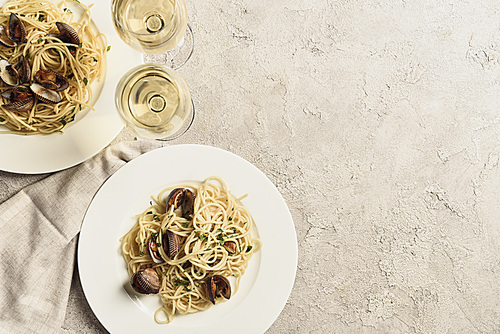 top view of delicious pasta with seafood served with white wine on textured grey surface with copy space