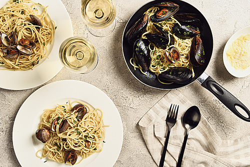 top view of delicious pasta with seafood served with white wine on textured grey surface