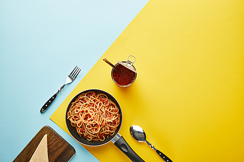 flat lay with delicious spaghetti with tomato sauce with parmesan on blue and yelow background