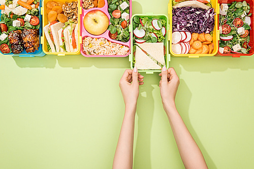 cropped view of woman choosing lunch boxes with food