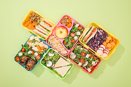flat lay of lunch boxes with food on green background