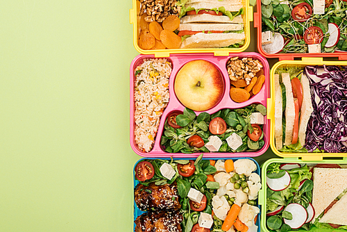 top view of lunch boxes with food on green background